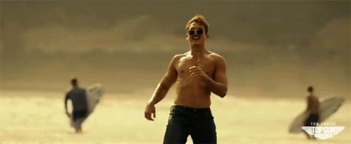 A Man Without A Shirt Is Running On A Beach With Top Gun America Written On The Bottom Right GIF