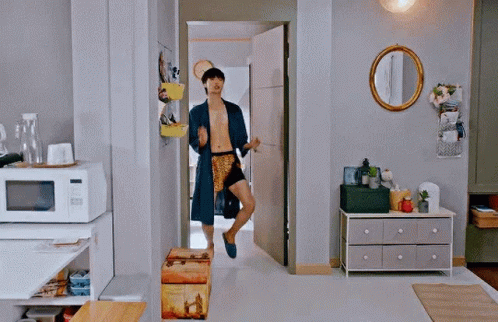 A Man Without A Shirt Is Running Through A Living Room In A Robe . GIF