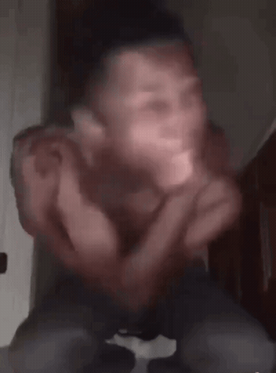 A Man Without A Shirt Is Sitting Down With His Arms Outstretched And His Eyes Glowing In The Dark . GIF