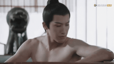 A Man Without A Shirt Is Sitting In A Bathtub With A Statue In The Background GIF