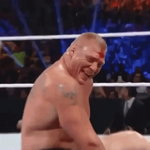 A Man Without A Shirt Is Sitting In A Wrestling Ring Laughing . GIF