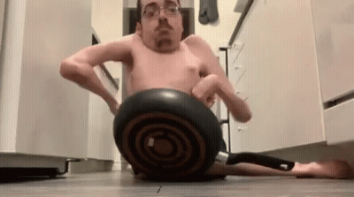 A Man Without A Shirt Is Sitting On A Pan On The Floor GIF