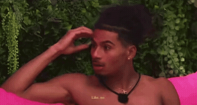 A Man Without A Shirt Is Sitting On A Pink Couch And Talking To Another Man . GIF