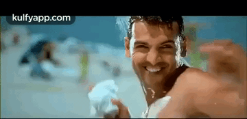 A Man Without A Shirt Is Smiling While Holding A Towel In His Hand . GIF