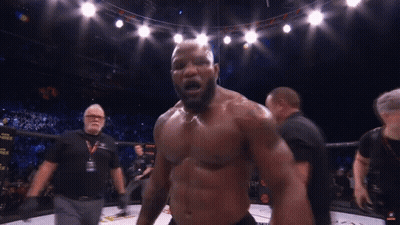 A Man Without A Shirt Is Standing In A Boxing Ring With A Referee Behind Him GIF