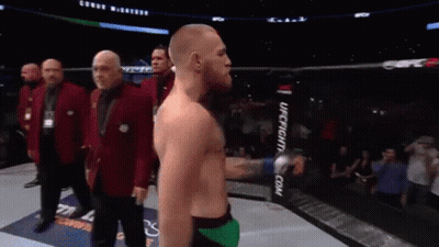 A Man Without A Shirt Is Standing In A Boxing Ring With His Arms Outstretched . GIF