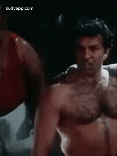 A Man Without A Shirt Is Standing In A Boxing Ring With His Hands Outstretched . GIF