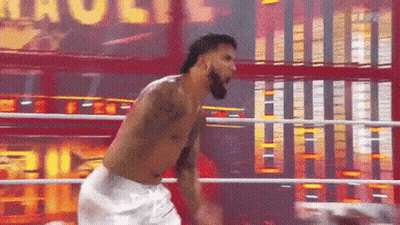 A Man Without A Shirt Is Standing In A Boxing Ring With The Word Hulk Behind Him GIF