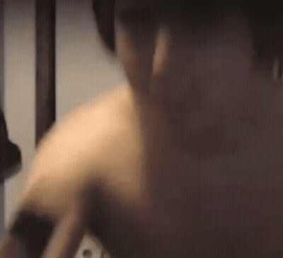 A Man Without A Shirt Is Standing In A Dark Room With Headphones On . GIF