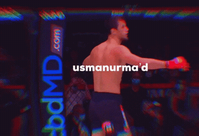 A Man Without A Shirt Is Standing In A Dark Room With The Words Usmanurma 'D Above Him GIF