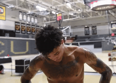 A Man Without A Shirt Is Standing In A Gym With A Sign That Says U On It GIF