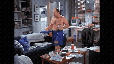 A Man Without A Shirt Is Standing In A Living Room With A Newspaper On The Coffee Table GIF