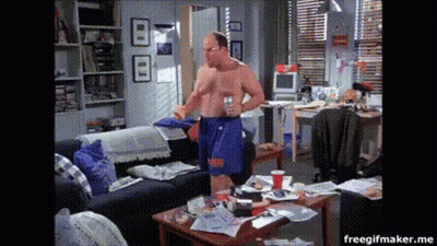 A Man Without A Shirt Is Standing In A Messy Room GIF