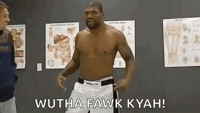 A Man Without A Shirt Is Standing In A Room With A Man Standing Next To Him . GIF