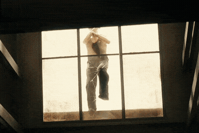A Man Without A Shirt Is Standing In A Window GIF
