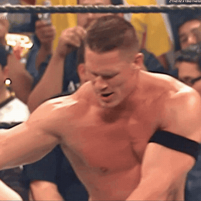 A Man Without A Shirt Is Standing In A Wrestling Ring With A Crowd Behind Him . GIF