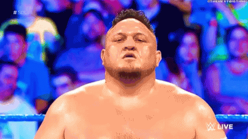 A Man Without A Shirt Is Standing In A Wrestling Ring With A Crowd In The Background . GIF