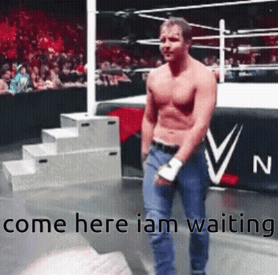 A Man Without A Shirt Is Standing In A Wrestling Ring With The Words Come Here I Am Waiting . GIF