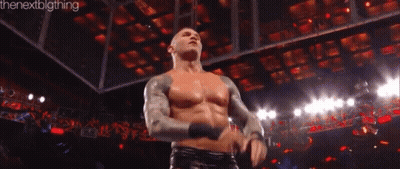 A Man Without A Shirt Is Standing In Front Of A Crowd In A Wrestling Ring . GIF