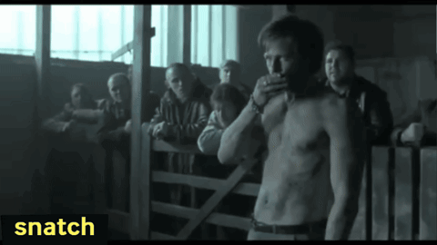 A Man Without A Shirt Is Standing In Front Of A Group Of People With Snatch Written On The Bottom Right GIF