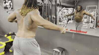 A Man Without A Shirt Is Standing In Front Of A Mirror In A Gym GIF
