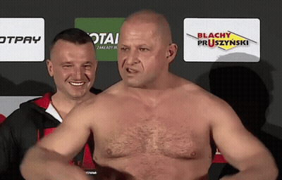 A Man Without A Shirt Is Standing In Front Of A Sign That Says Blachy Pruszzynski GIF