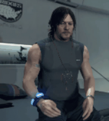 A Man Without A Shirt Is Standing In Front Of A Wall With A Sticker That Says Riders GIF