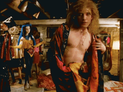 A Man Without A Shirt Is Standing In Front Of Mannequins In A Room GIF