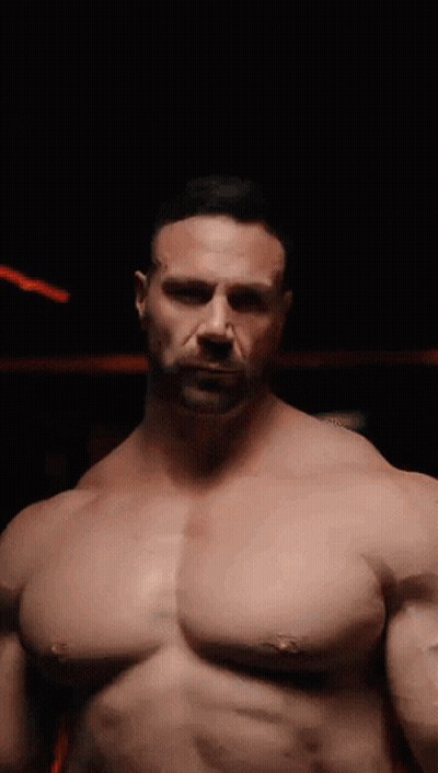 A Man Without A Shirt Is Standing In The Dark GIF