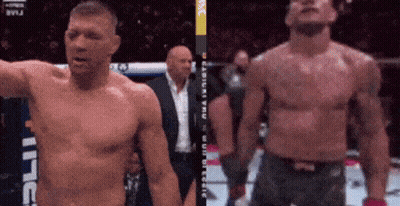 A Man Without A Shirt Is Standing Next To Another Shirtless Man In A Boxing Ring GIF