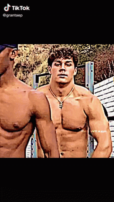 A Man Without A Shirt Is Standing Next To Another Shirtless Man With A Necklace Around His Neck .. GIF