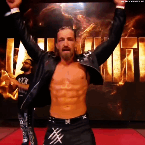 A Man Without A Shirt Is Standing On A Red Carpet With His Arms Outstretched . GIF