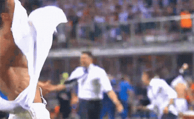 A Man Without A Shirt Is Standing On A Soccer Field With A White Shirt On GIF