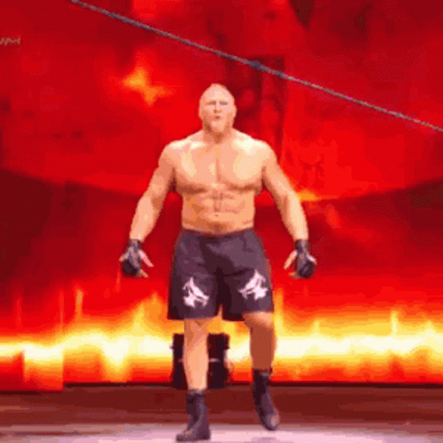 A Man Without A Shirt Is Standing On A Stage In Front Of A Fire Background . GIF