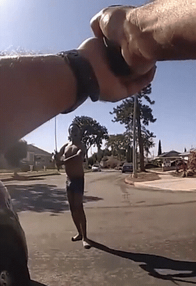 A Man Without A Shirt Is Standing On A Street Holding A Fishing Rod GIF