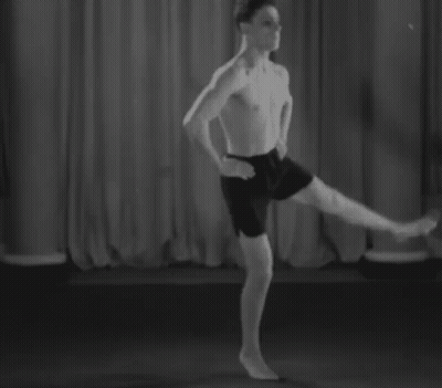 A Man Without A Shirt Is Standing On One Leg On A Stage In A Black And White Photo . GIF