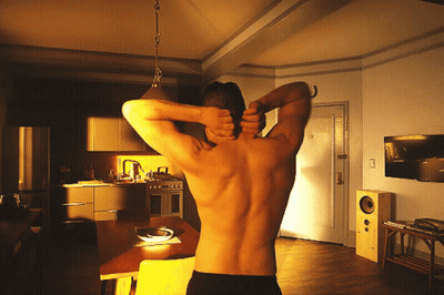 A Man Without A Shirt Is Stretching His Back In A Kitchen GIF