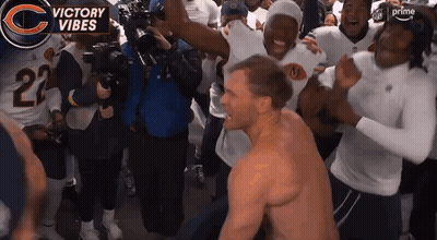 A Man Without A Shirt Is Surrounded By A Group Of Players And A Banner That Says Victory Vibes GIF