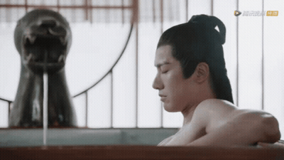 A Man Without A Shirt Is Taking A Bath In A Bathtub In Front Of A Statue Of A Dragon GIF