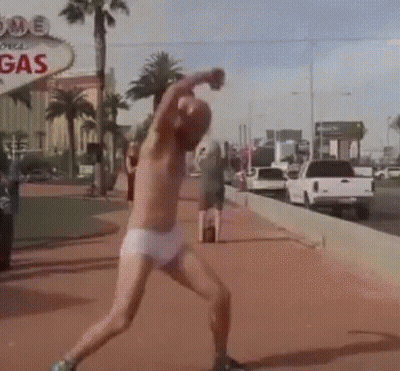 A Man Without A Shirt Is Throwing A Ball In Front Of A Sign That Says Gas GIF
