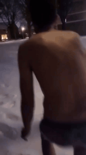 A Man Without A Shirt Is Walking In The Snow At Night GIF