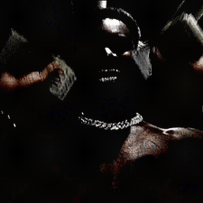 A Man Without A Shirt Is Wearing A Chain Around His Neck In A Dark Room . GIF