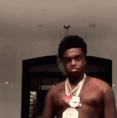 A Man Without A Shirt Is Wearing A Necklace And Earrings . GIF