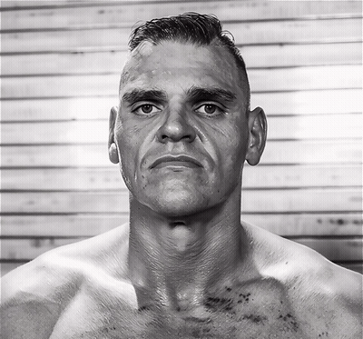 A Man Without A Shirt Looks At The Camera With A Serious Look On His Face GIF
