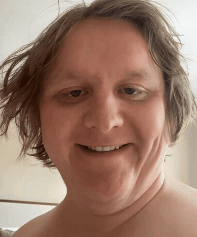 A Man Without A Shirt Smiles For The Camera GIF