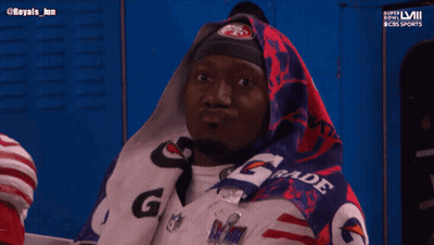 A Man Wrapped In A Gatorade Blanket Looks At Something GIF