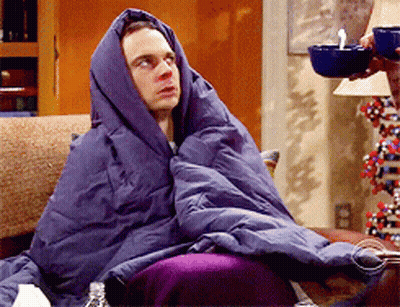 A Man Wrapped In A Purple Blanket Sits On A Couch GIF