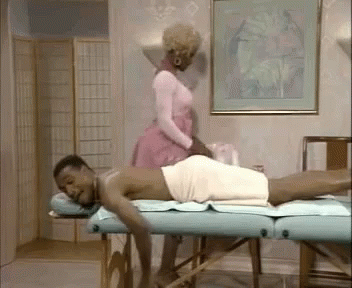 A Man Wrapped In A Towel Is Getting A Massage From A Woman In A Pink Dress . GIF