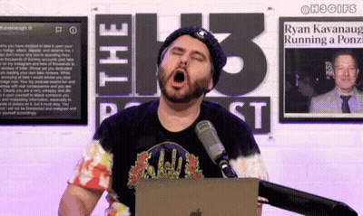A Man Yawning In Front Of A Microphone In Front Of A Sign That Says The 13 Podcast GIF