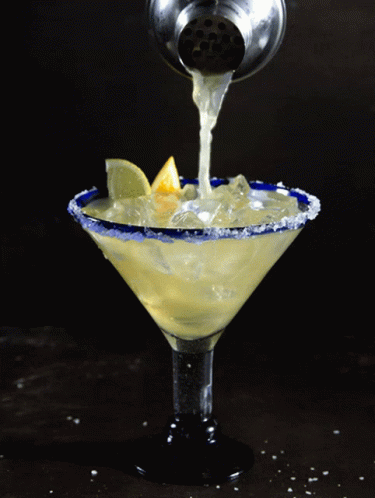 A Martini Is Being Poured Into A Martini Glass GIF